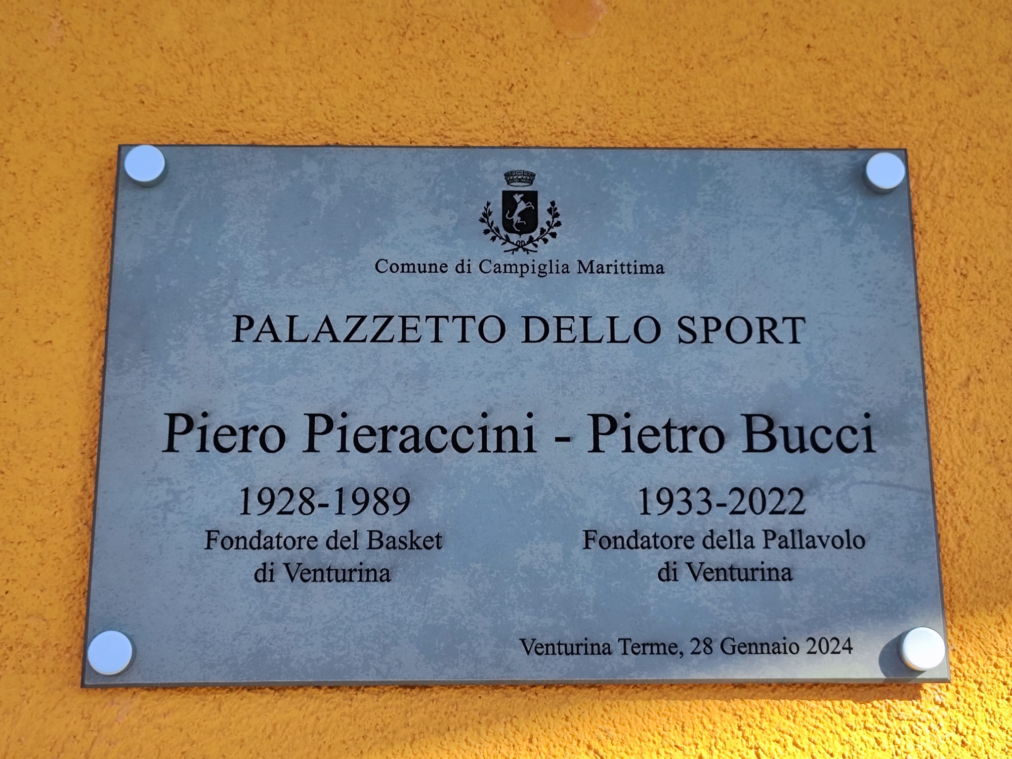 La targa affissa tra le due porte principali del palazzetto di via Montale